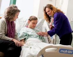 Patient in hospital bed with two provider - simulation patient